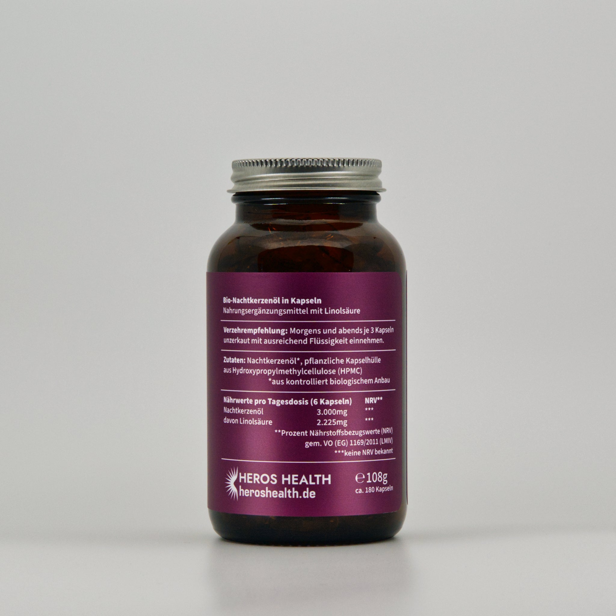 back view of amber glass with organic evening primrose oil capsules on light background 